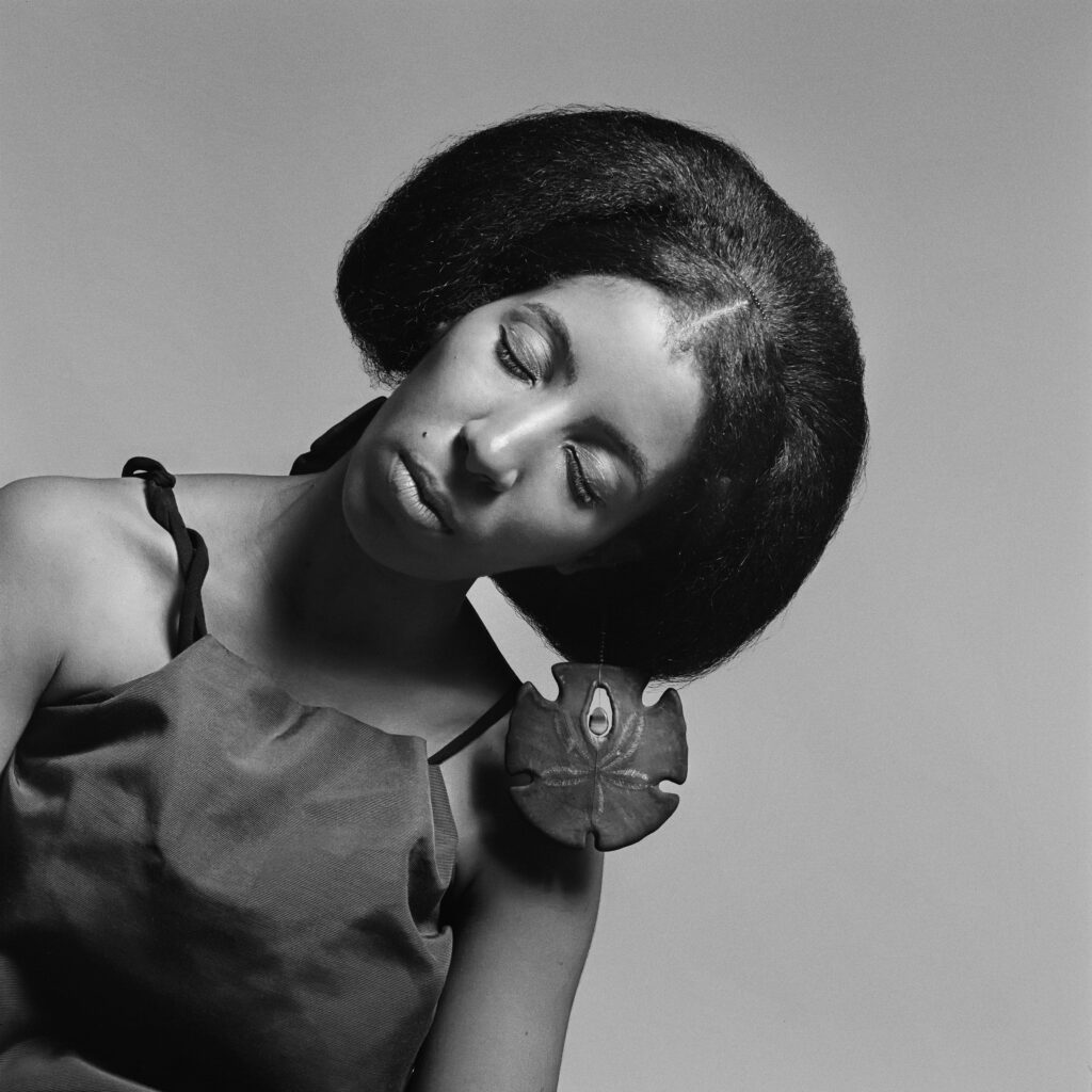 Black and white portrait of brown skinned woman leaning sideways wearing a large shell earring