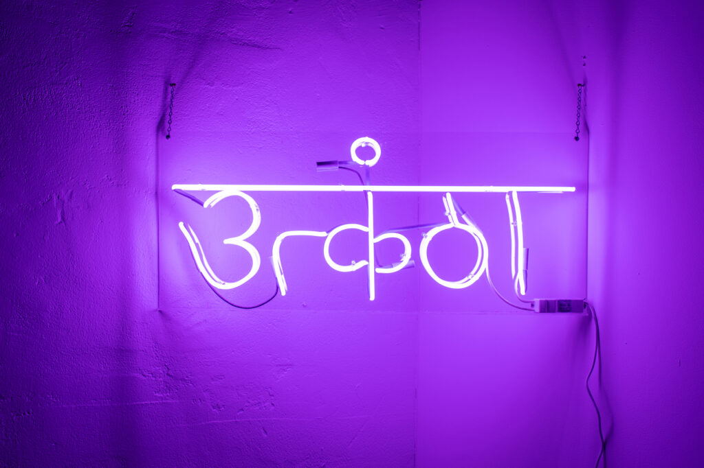 Neon letters illuminate wall in purple light.