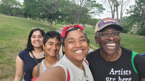 Four people take a selfie together in a park.