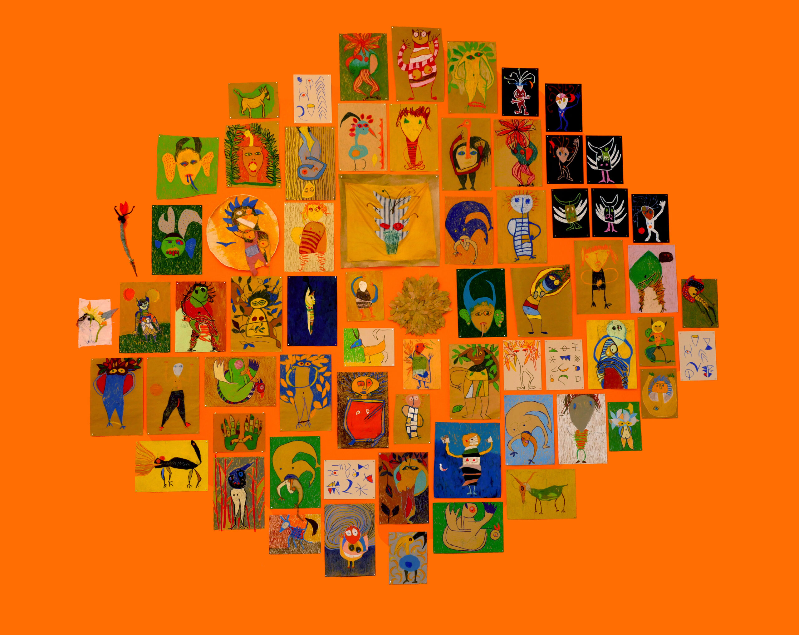 Many small, multicolored drawings of demons arranged on bright orange wall.