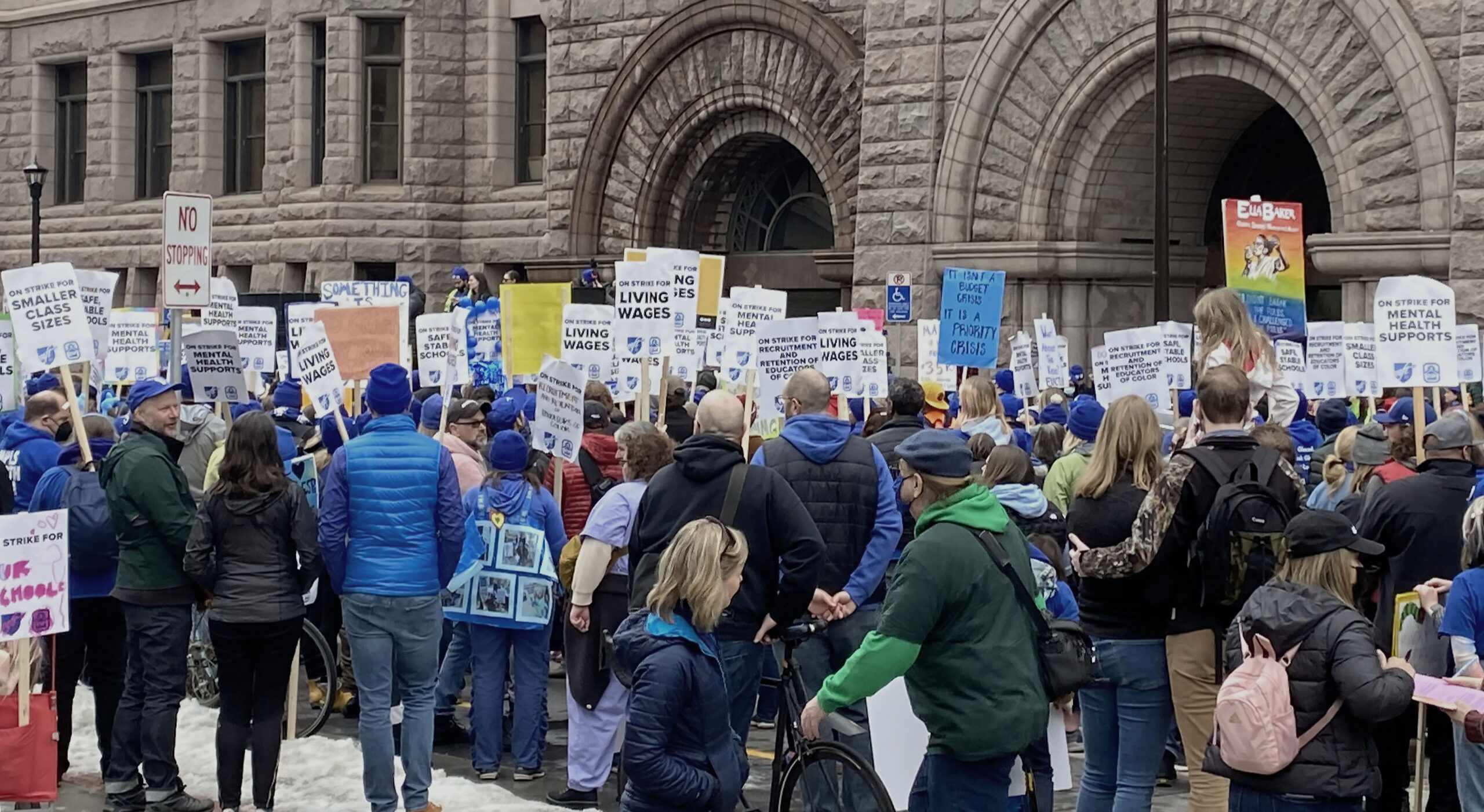 Protesters carrying signs outside of stone building.