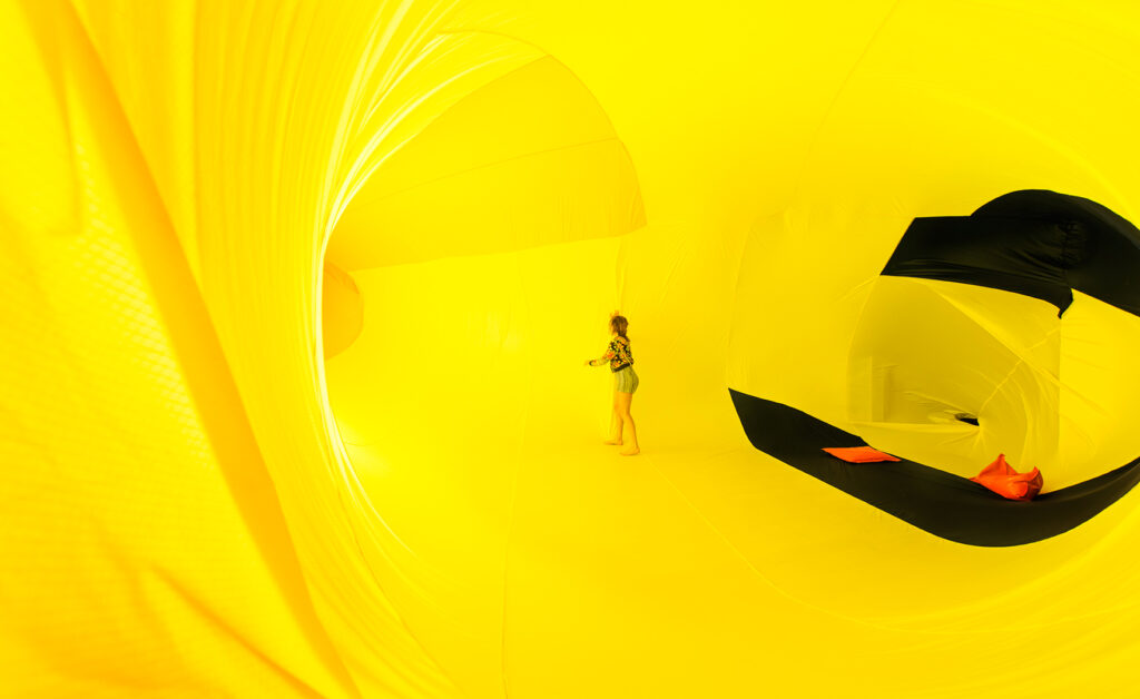 Person inside a large, bright yellow balloon-like object.