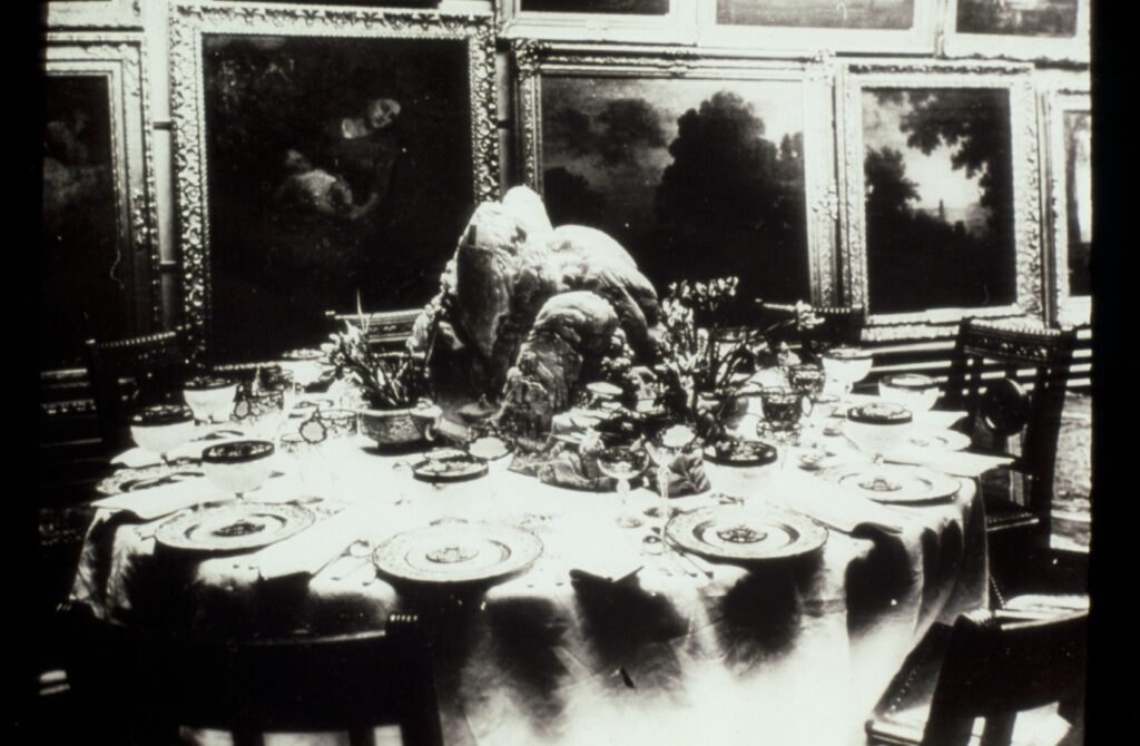 Black and white photo of ornate table setting with jade sculpture as centerpiece.
