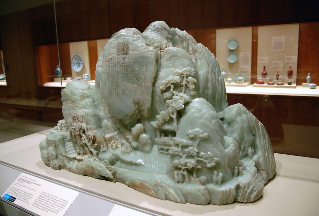Jade sculpture of mountain with trees and fine details.
