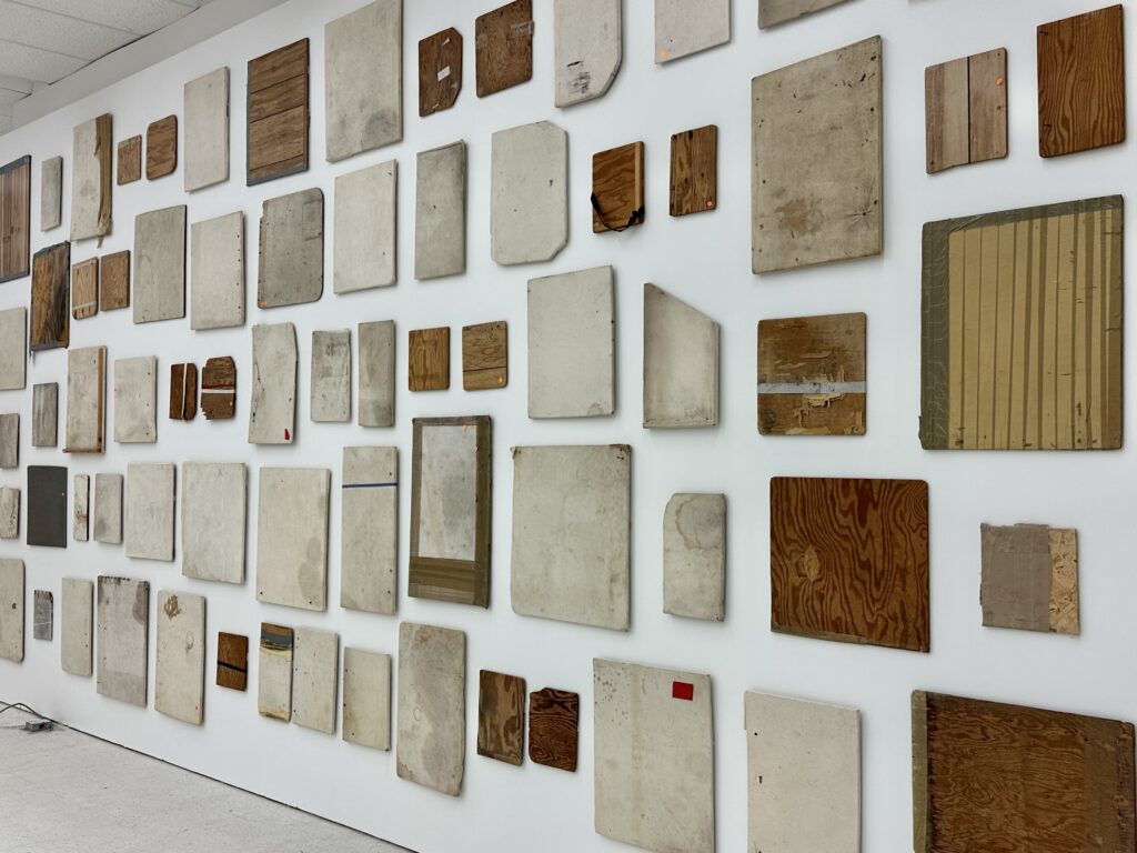 Many off-white and wooden square and rectangular shapes mounted on white wall.