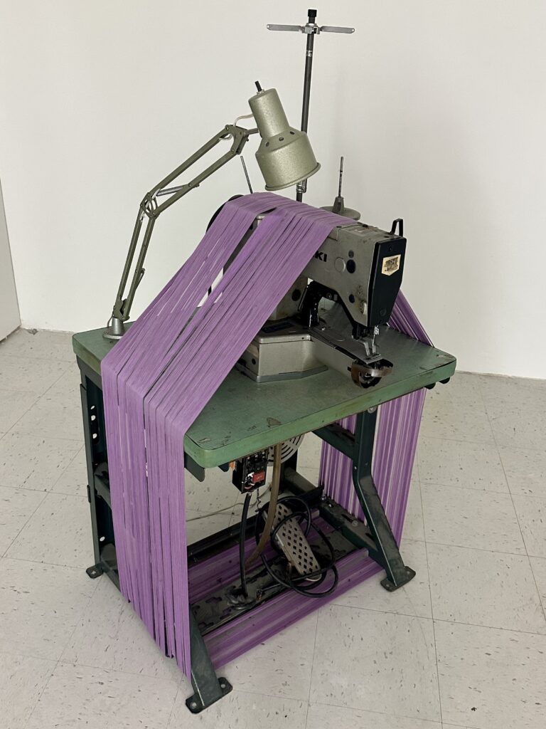 Sculpture made of sewing machine wrapped in purple thread.
