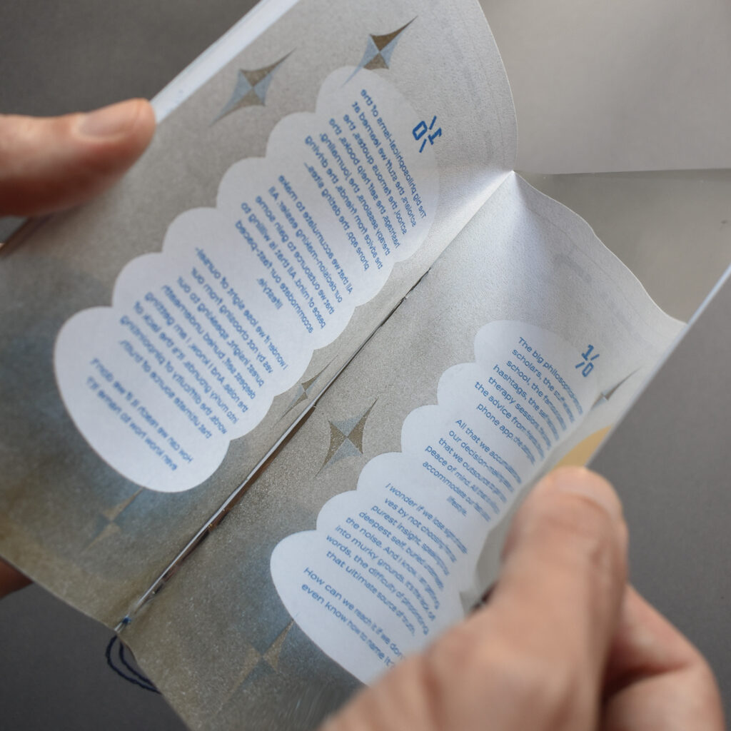 Hands hold printed book with silver page and blue text
