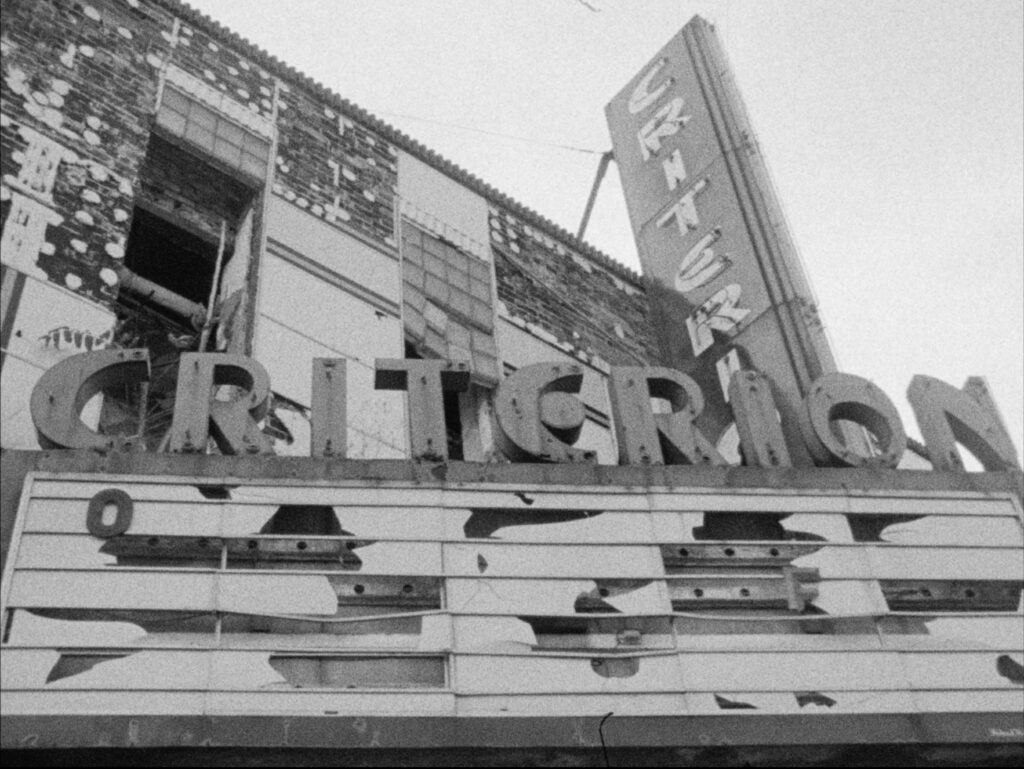 Black and white film still of vintage marquis reading CRITERION.