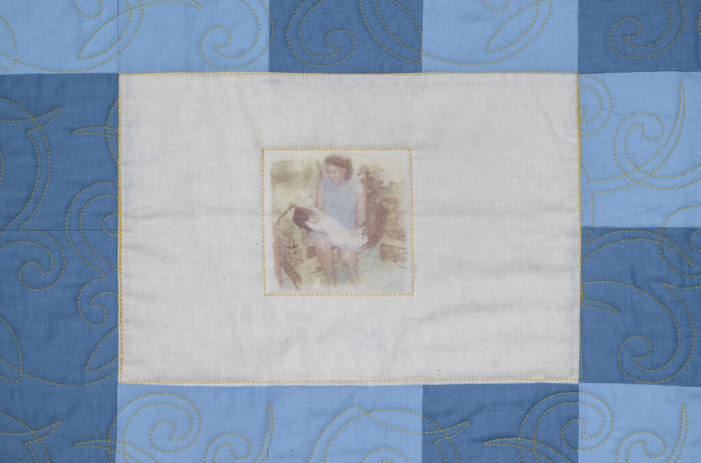 Detail of quilt with blue border and white center with vintage photograph.