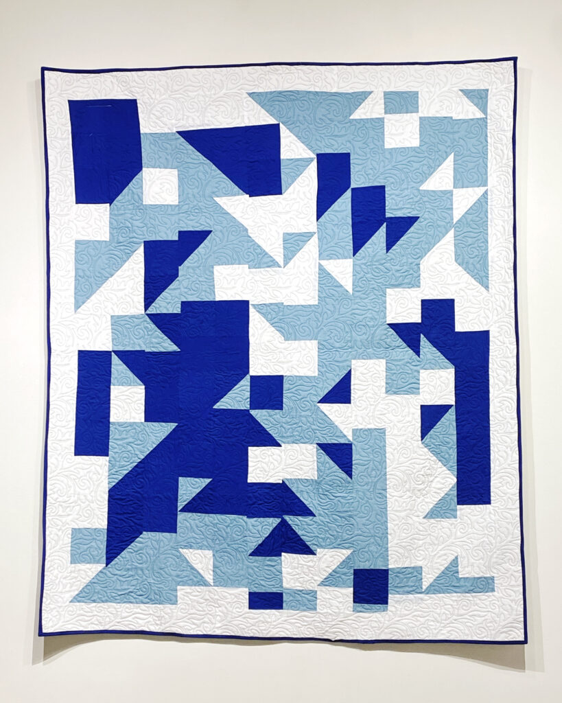 Quilt with white, blue, and light blue asymmetrical pattern.