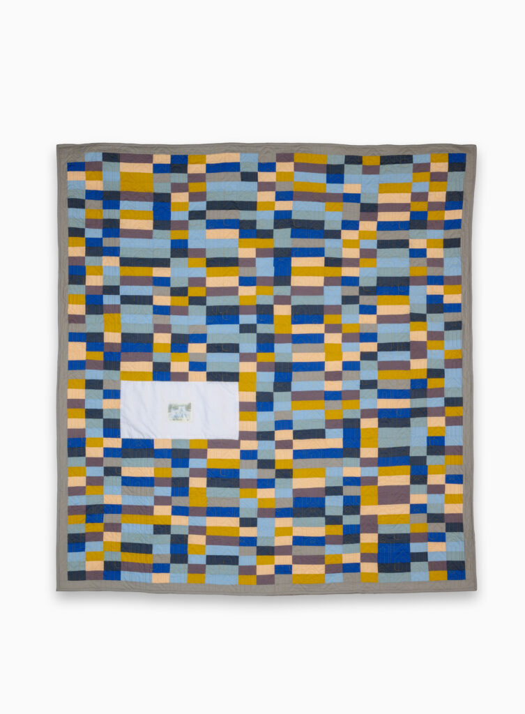 Quilt with many small pieces of fabric in shades of blue and brown.