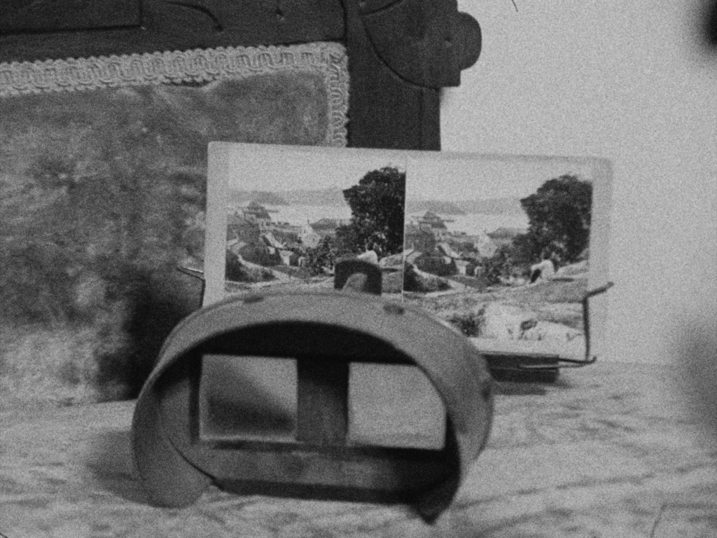 Black and white film still with vintage viewfinder and old photographs.