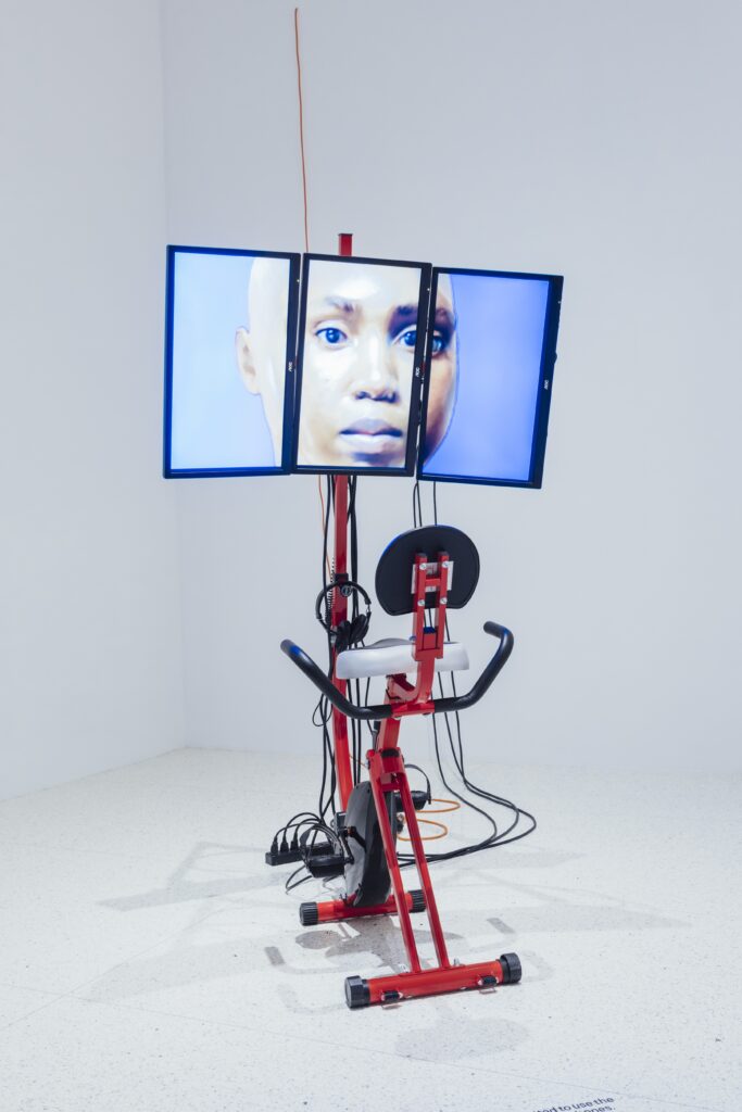Red exercise bike with three screens showing a face