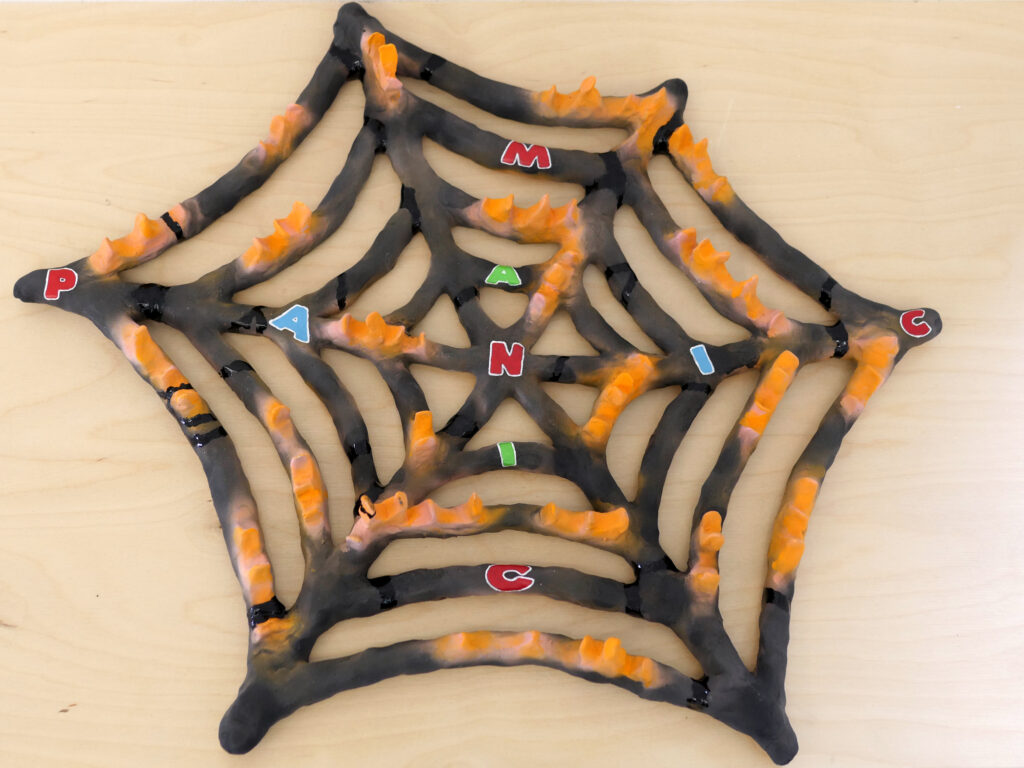 Ceramic spiderweb with letters and raised orange spikes