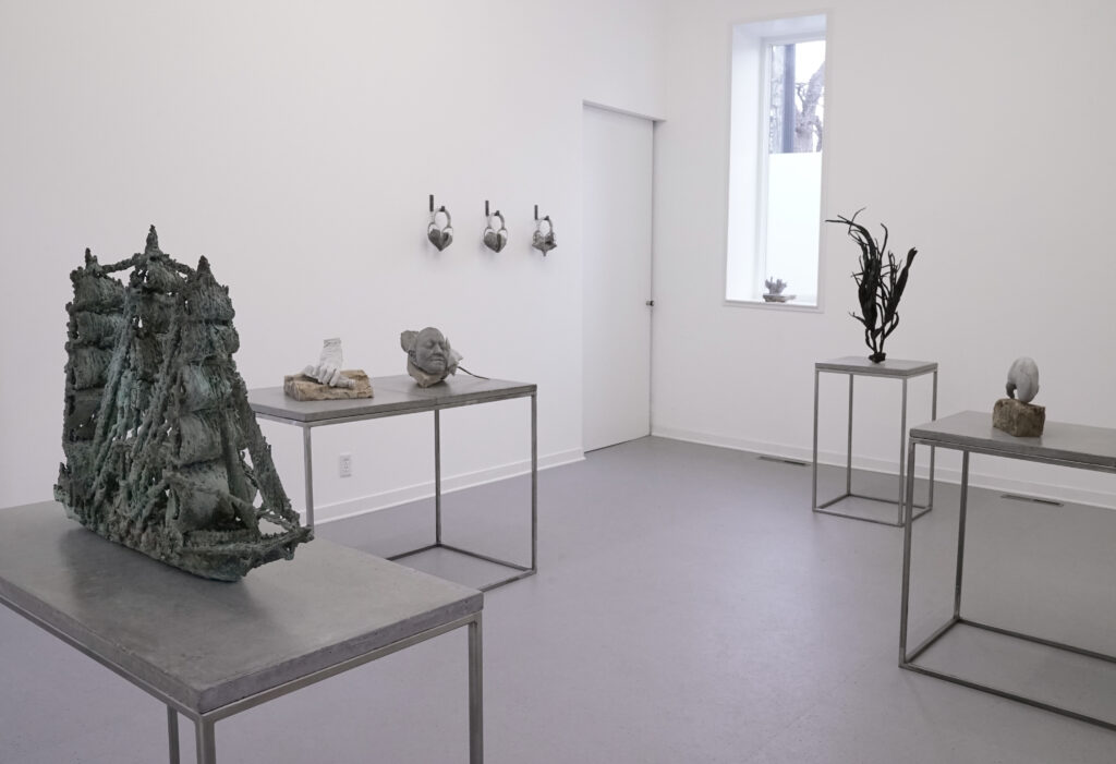 White-walled gallery with items of cast stone and bronze arranged on tables