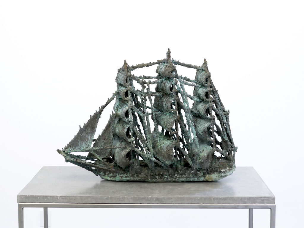Old weathered ship cast in bronze on concrete table