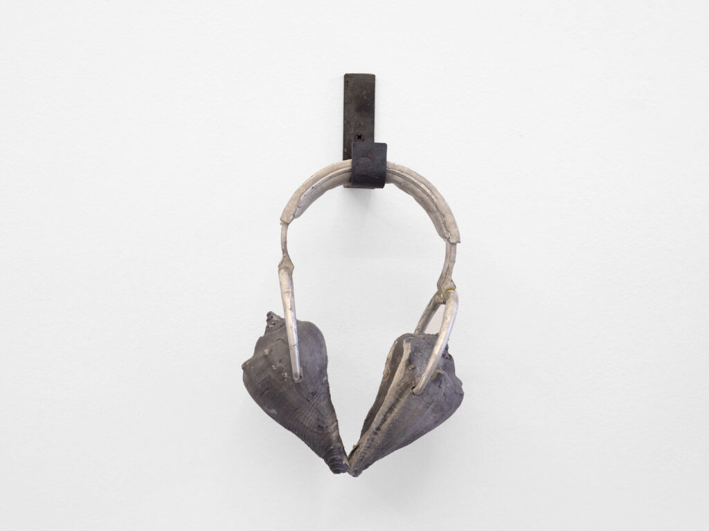 Pair of headphones made of cast concrete sheashells hanging on iron hook