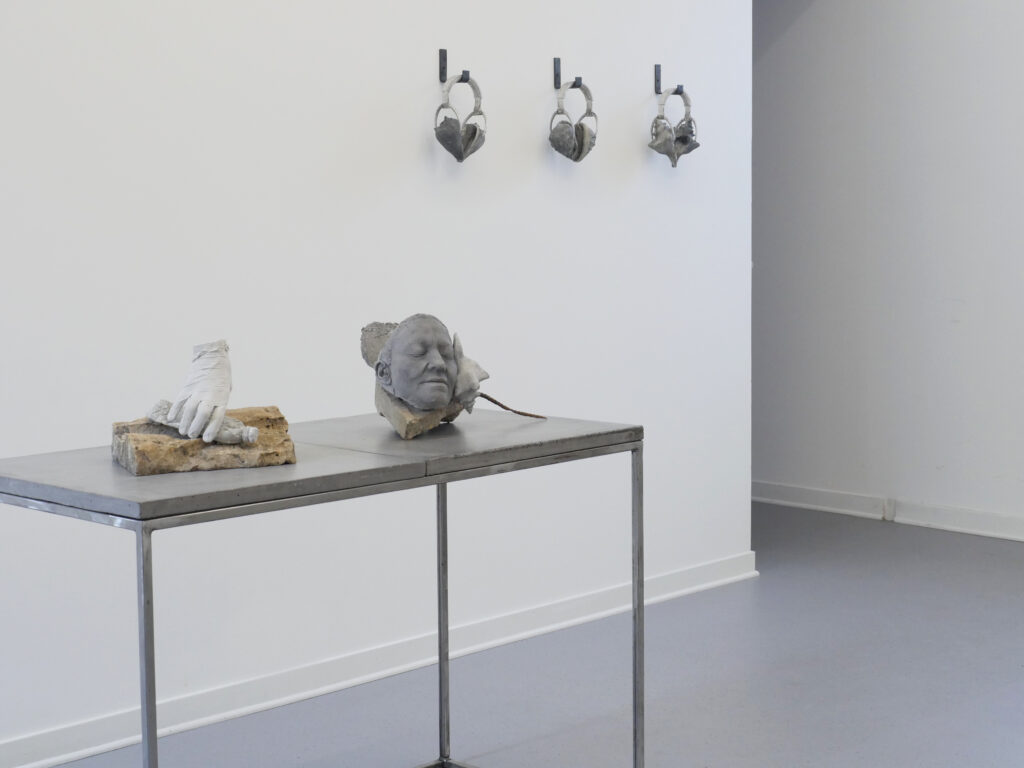 White-walled gallery with items of cast stone and bronze arranged on a table