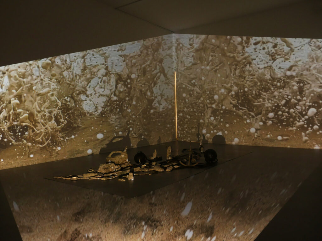 Cast concrete objects spread across floor with projection of water on walls and floor