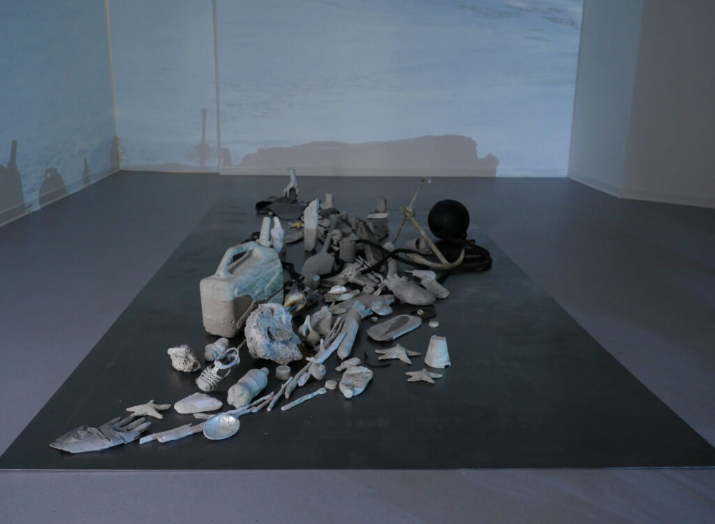 Cast concrete objects spread across floor with projection on walls and floor
