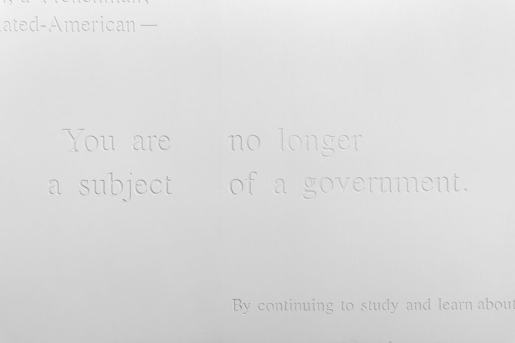 Text etched into white drywall reads "You are no longer a subject of government"