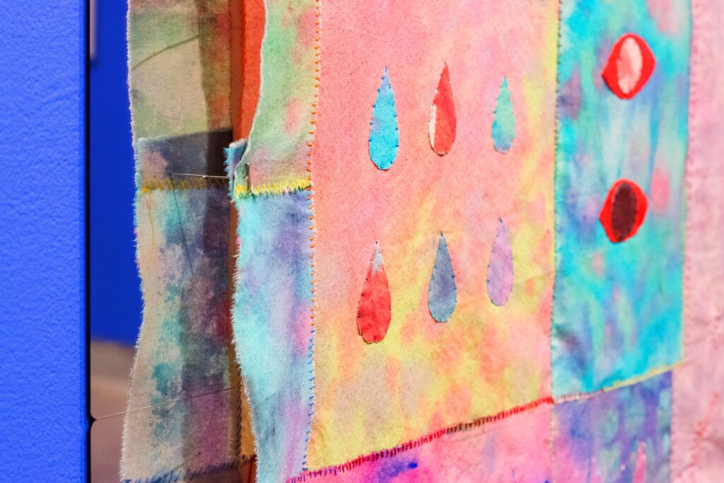 Pastel dyed cloth hand-stitched together with droplets and eyes
