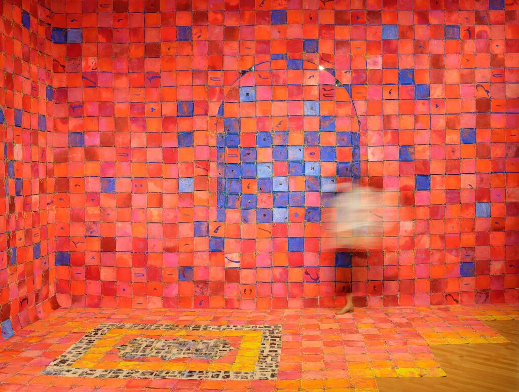 Blurred person in space with tiles of dyed cloth sewn together covering walls and floor