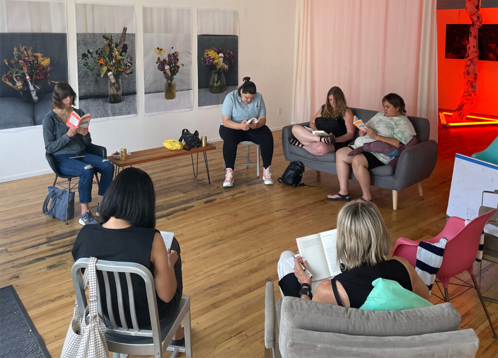 Group of people reading in a gallery in an assortment of chairs