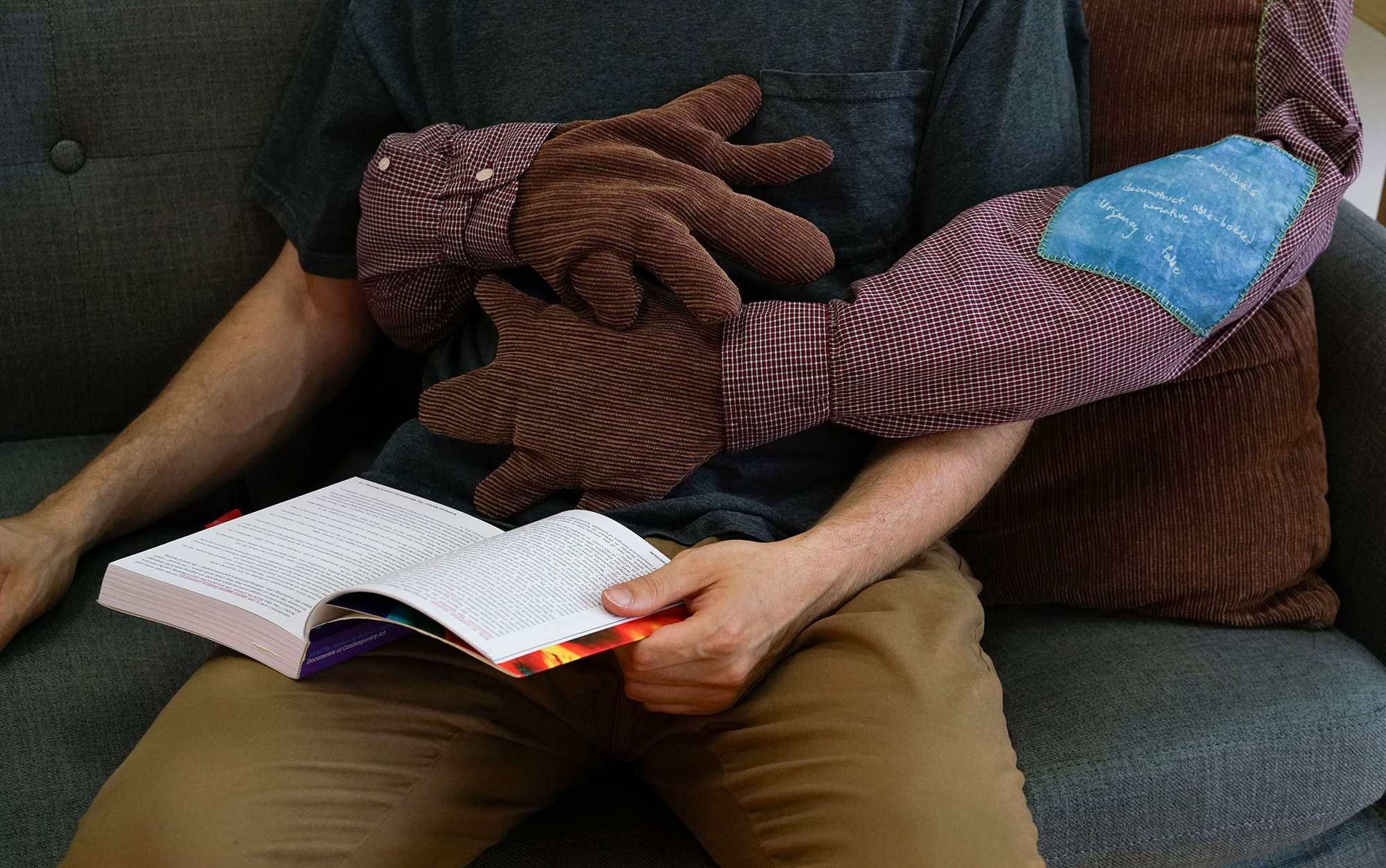 Person sitting reading a book with pillow with sewn arms wrapping around them