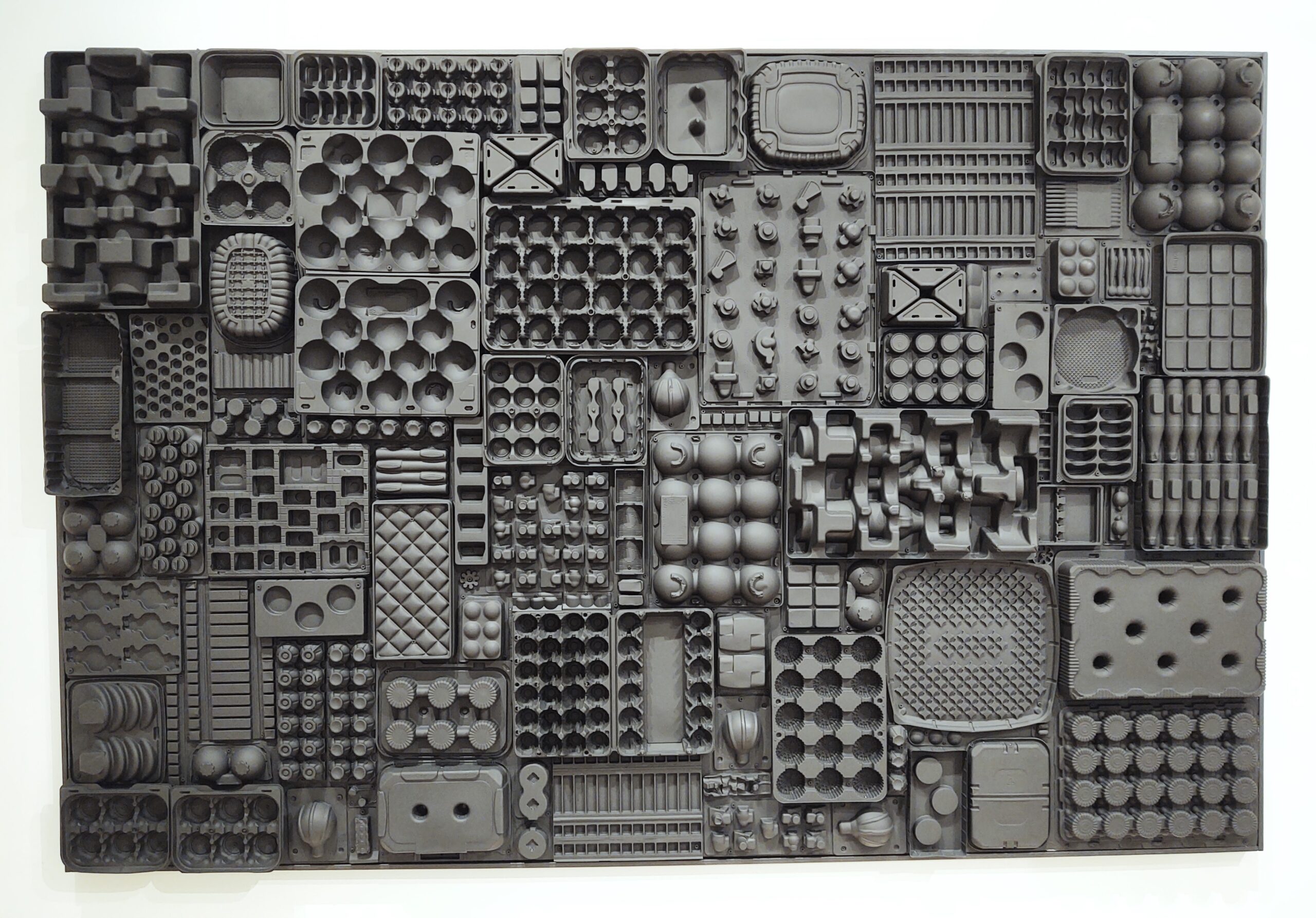 Large rectangle made of black plastic molded trays of various shapes.