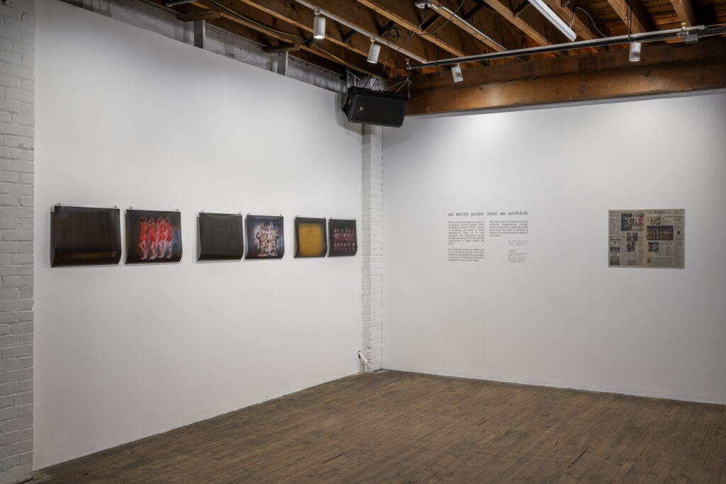 Corner of a gallery with dance portrait images, newspaper, and exhibition description.