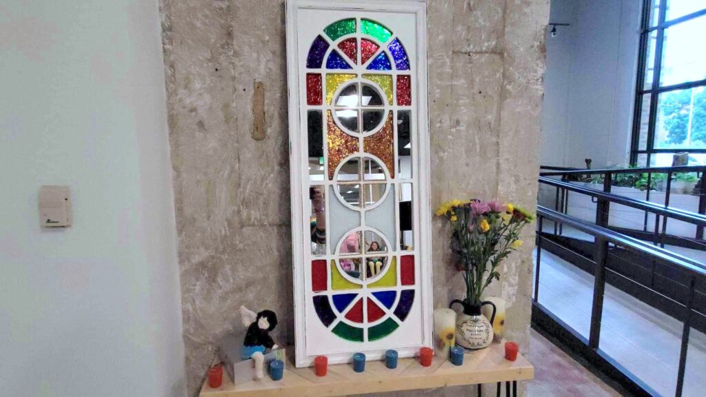 Altar with colorful stained glass window on table with flowers and candles