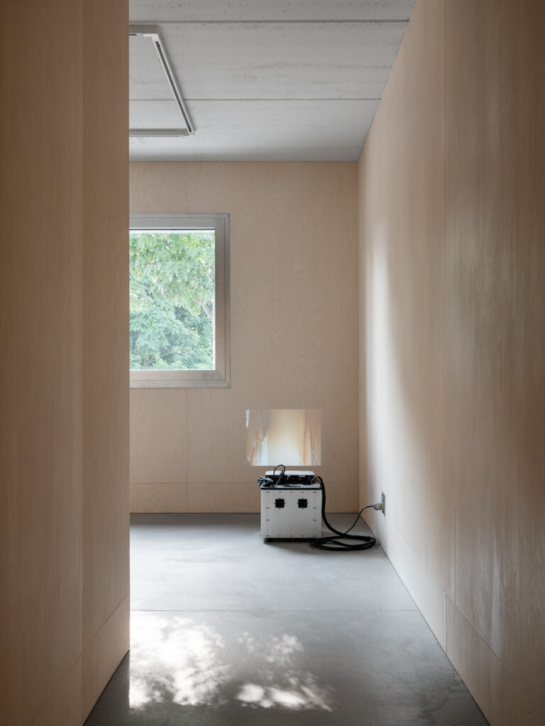 Wood paneled room with small white box plugged into wall, projecting onto wall in front