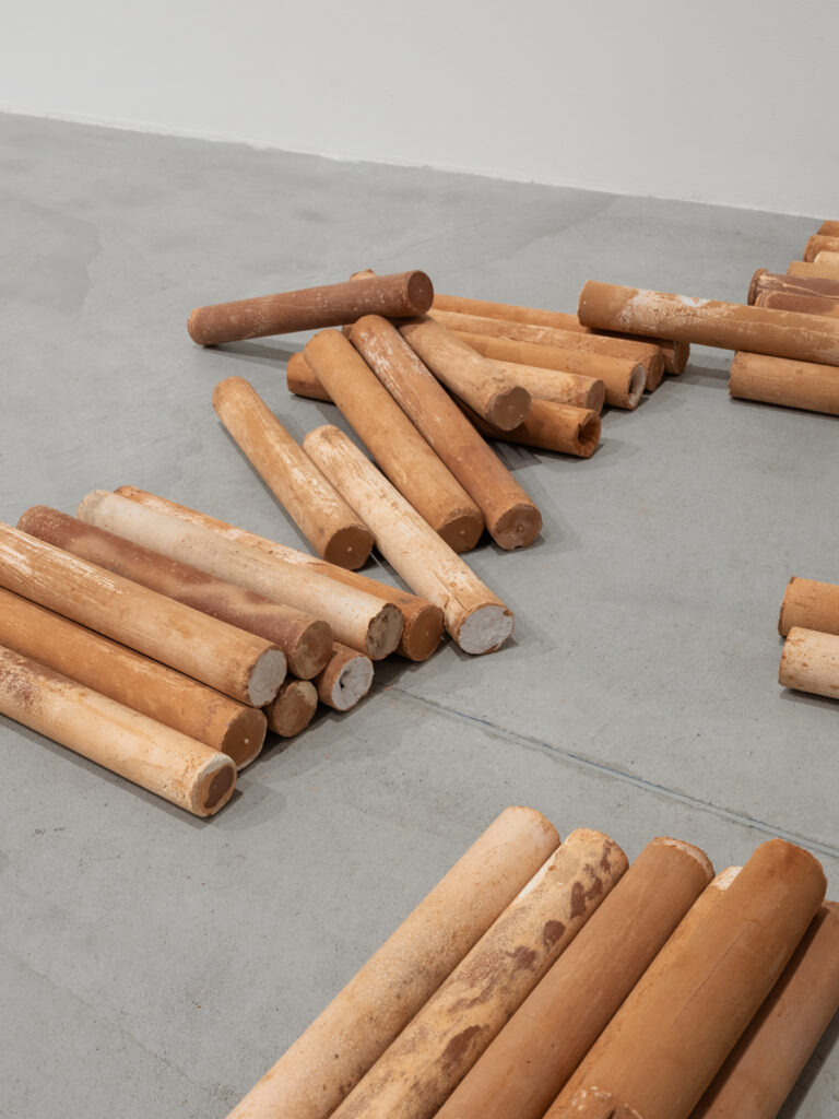 Brown dowels spread and in small stacks on concrete floor