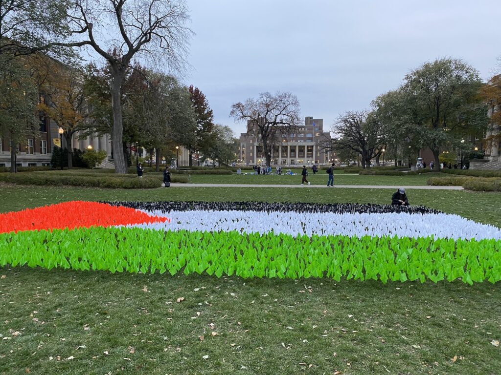 Many small flags placed in university lawn forming the shape of the Palestinian flag.