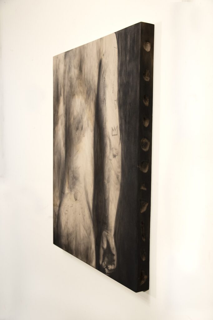 Side view of charcoal drawing on wood panel of person's nude back torso and right arm, divots carved into side of panel