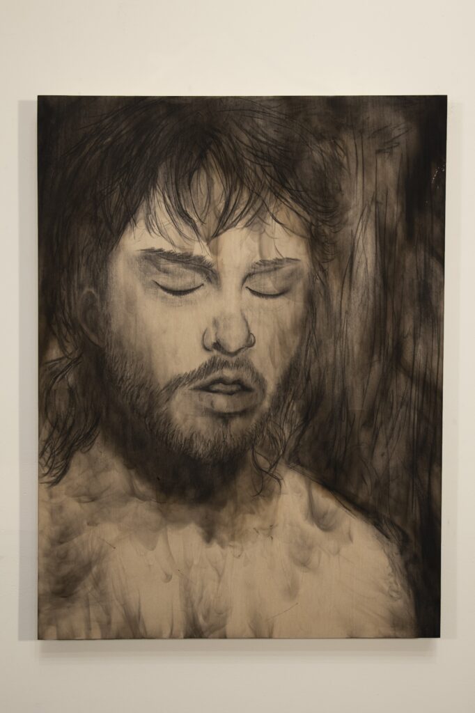 Charcoal portrait drawing of person with closed eyes and mouth slightly open